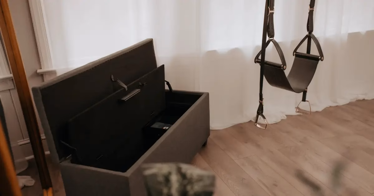 Image shows a sex swing next to an open storage bench with hidden, locking storage compartment.